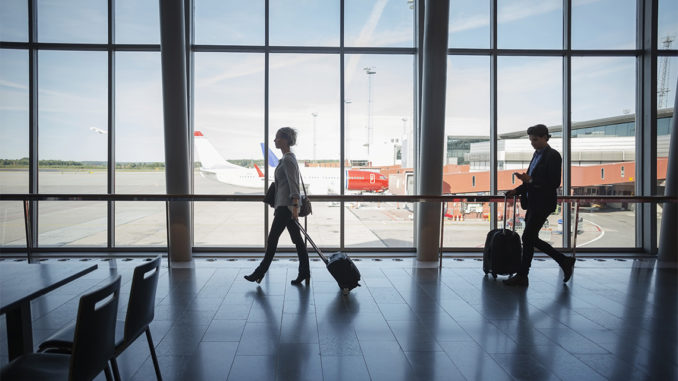 Side view of business people walking with luggage at airport